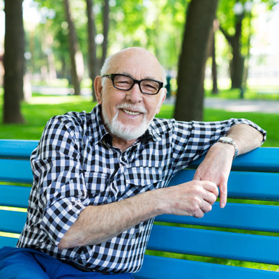 Elderly man sitting outdoors on bright blue bench